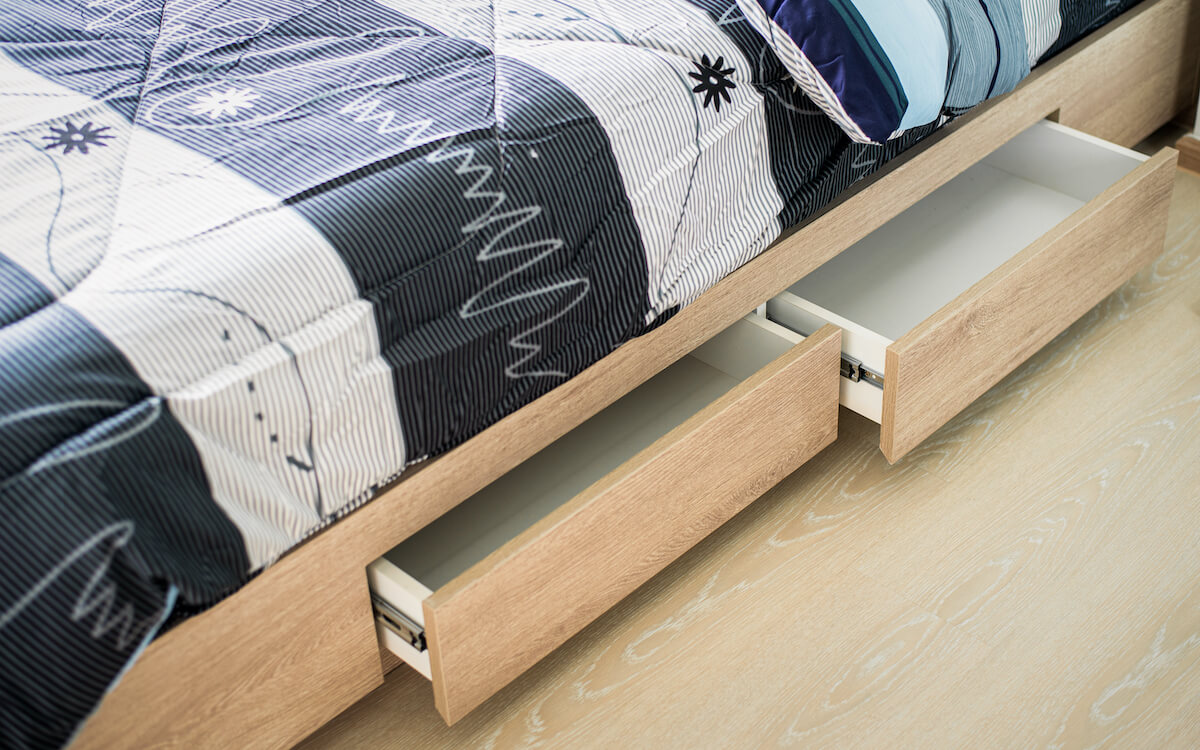 Opened wooden drawers that are built into the frame of a bed